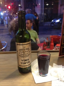 Tiny bottle of wine with a glass that is probably highly appropriate to Spanish culture. 